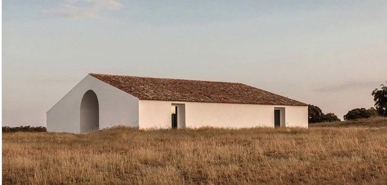 Architektur von alma blanca: gekalktes Haus mit Ziegeldach und offenem Bogengang im trockenen Gras des Campo