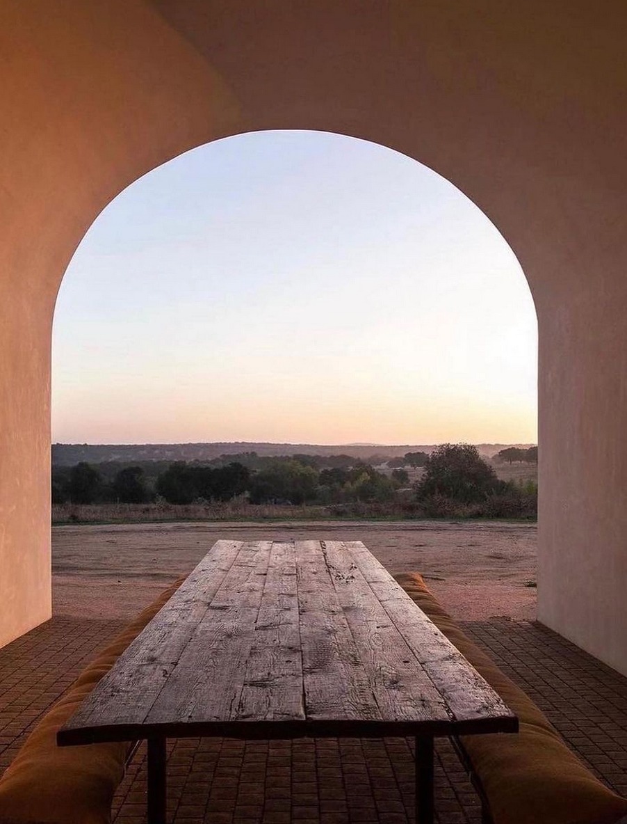 Blick durch den gekalkten Bogen von alma blanca auf die Landschaft bei Sonnenuntergang, gedeckter Holztisch im Vordergrund