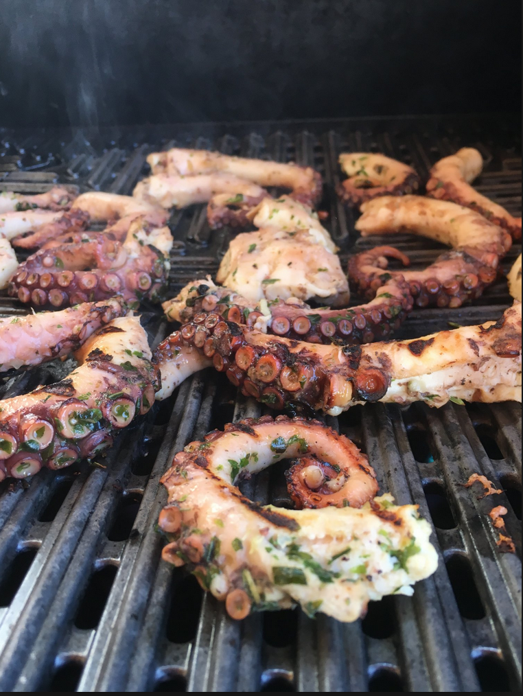 Oktopus-Arme grillen über offener Glut, mit Kräutern mariniert