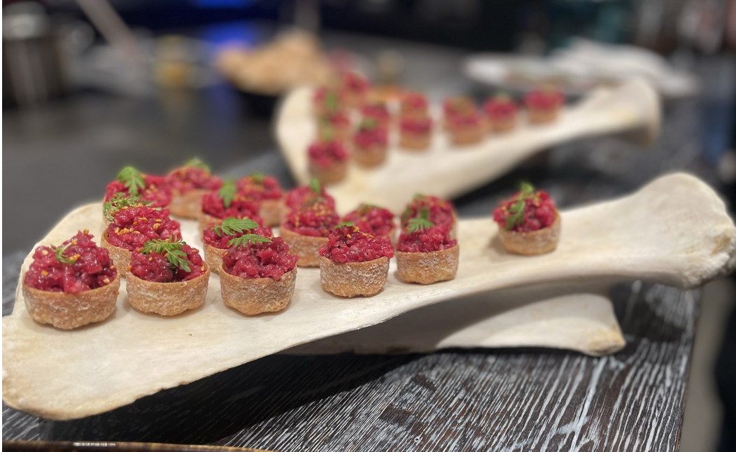 Fein angerichtete Tartar-Häppchen, serviert auf einer Naturplatte